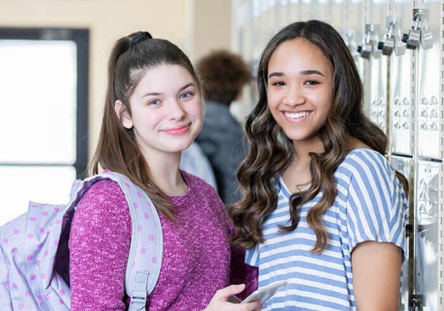 two students standing together in a classroom smiling