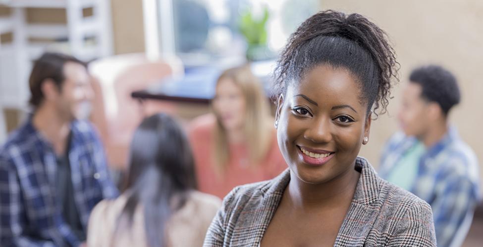 An African American woman stands confidently in front of her support group.