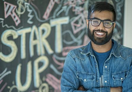 An entrepreneur standing in front of a black board with the words "start up"