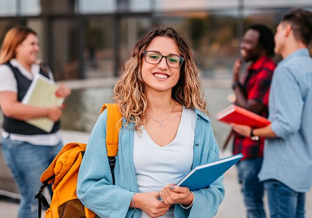 Smiling female college student with friends in the background