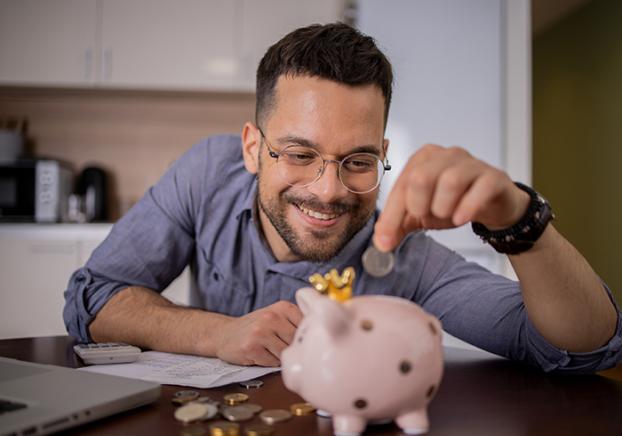 Male student saving money in a piggy bank